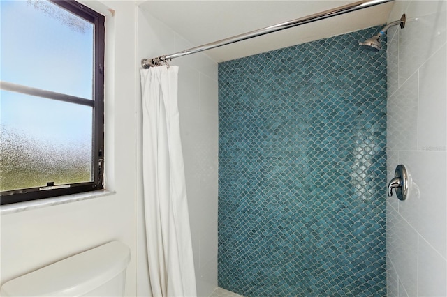 bathroom featuring tiled shower and toilet