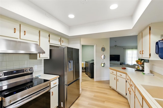 kitchen featuring washer and clothes dryer, light countertops, under cabinet range hood, and stainless steel appliances