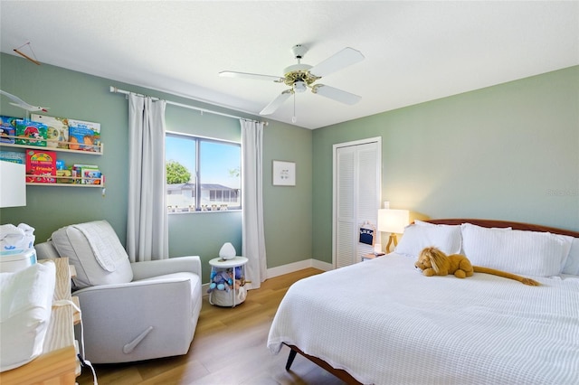 bedroom with ceiling fan, wood finished floors, a closet, and baseboards