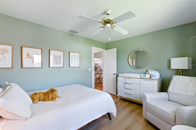 bedroom featuring ceiling fan, visible vents, and wood finished floors