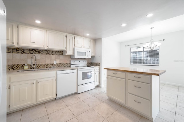 kitchen featuring a notable chandelier, a sink, tasteful backsplash, white appliances, and butcher block counters