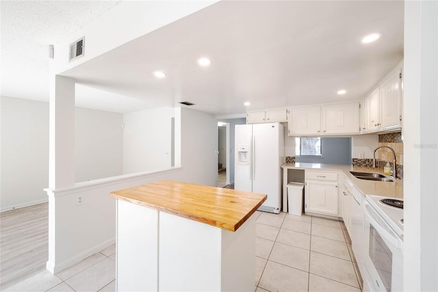 kitchen with white appliances, light tile patterned floors, visible vents, and a sink