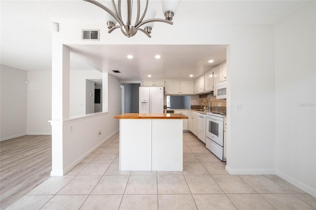 kitchen with white appliances, light tile patterned floors, visible vents, wooden counters, and a sink