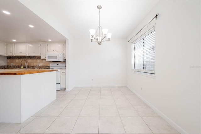 kitchen featuring white appliances, wood counters, white cabinetry, tasteful backsplash, and a chandelier