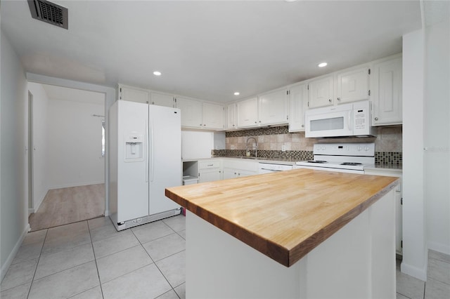 kitchen with white appliances, backsplash, and white cabinets