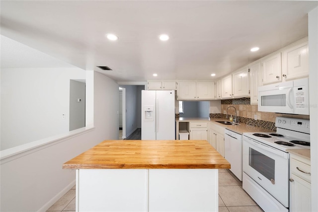 kitchen with light tile patterned floors, white cabinets, white appliances, and a sink