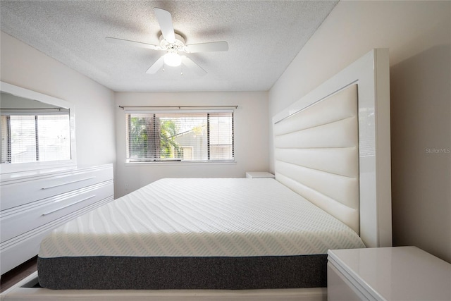 bedroom with a textured ceiling and a ceiling fan