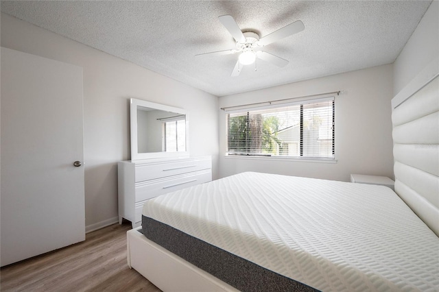 bedroom with ceiling fan, a textured ceiling, and light wood-style flooring