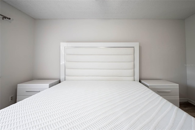 bedroom featuring a textured ceiling, baseboards, and dark wood-style flooring