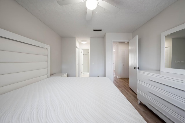 bedroom featuring visible vents, ensuite bath, ceiling fan, dark wood-type flooring, and a textured ceiling