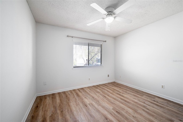 empty room with a textured ceiling, a ceiling fan, baseboards, and wood finished floors