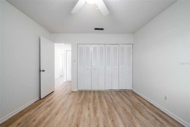 unfurnished bedroom featuring visible vents, a textured ceiling, wood finished floors, a closet, and baseboards