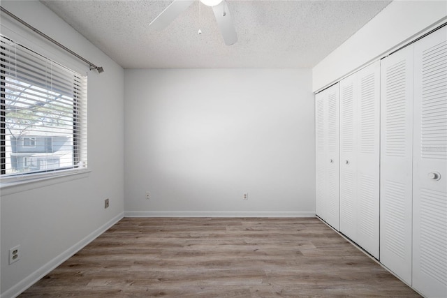 unfurnished bedroom with light wood-type flooring, baseboards, a textured ceiling, and a closet