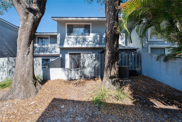 rear view of property with stucco siding, cooling unit, and fence