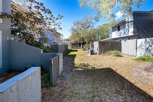 view of yard with central AC and fence