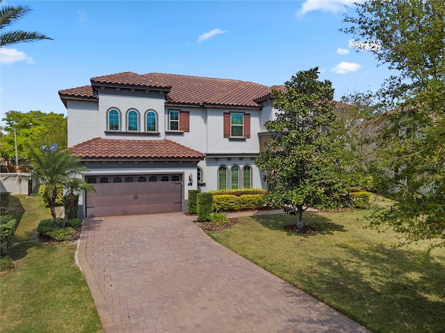 mediterranean / spanish-style house with stucco siding, a front lawn, decorative driveway, an attached garage, and a tiled roof