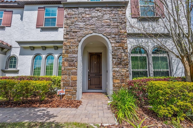 doorway to property with stucco siding and stone siding