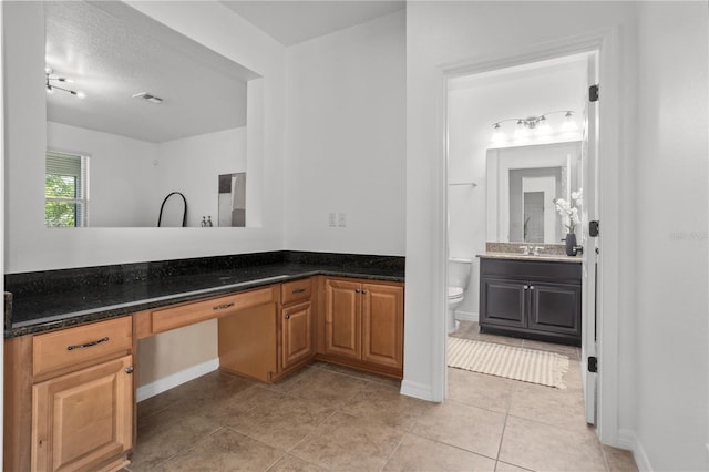 bathroom with tile patterned flooring, toilet, vanity, and baseboards