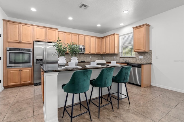 kitchen with visible vents, a breakfast bar, tasteful backsplash, a center island, and stainless steel appliances