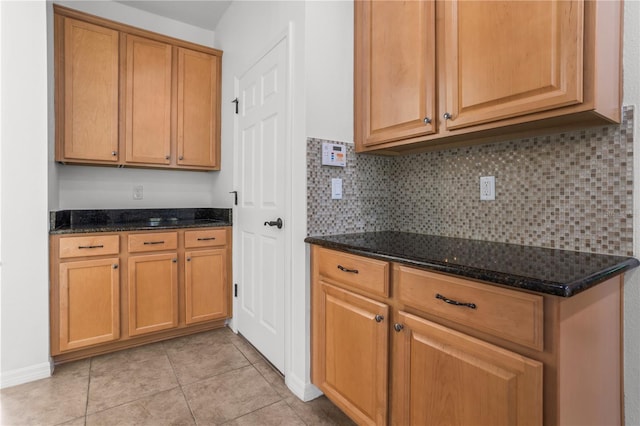 kitchen featuring dark stone countertops, tasteful backsplash, and light tile patterned floors