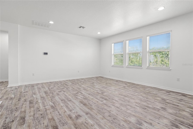 spare room featuring visible vents, a textured ceiling, wood finished floors, recessed lighting, and baseboards