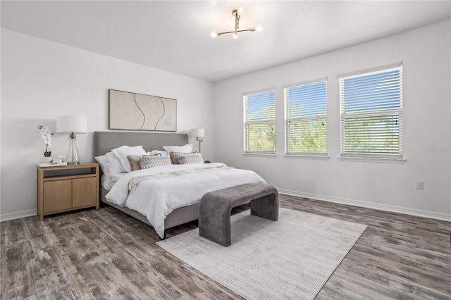 bedroom with baseboards, wood finished floors, and a chandelier