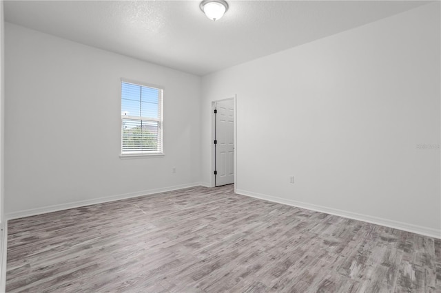 unfurnished room featuring baseboards, a textured ceiling, and light wood-style flooring