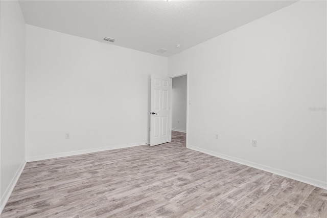 spare room with light wood-style flooring, baseboards, and visible vents