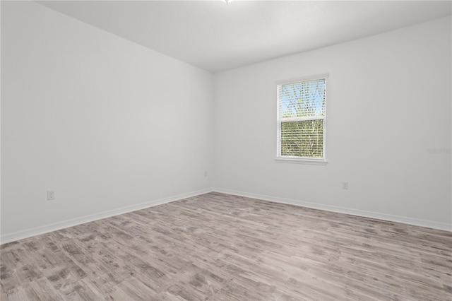 spare room featuring light wood-type flooring and baseboards