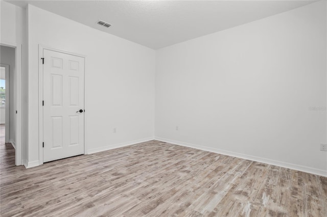 spare room featuring wood finished floors, visible vents, and baseboards