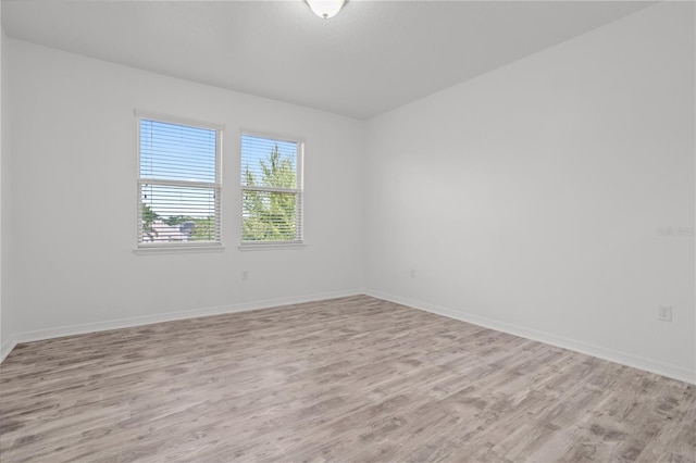 unfurnished room with baseboards and light wood-style floors