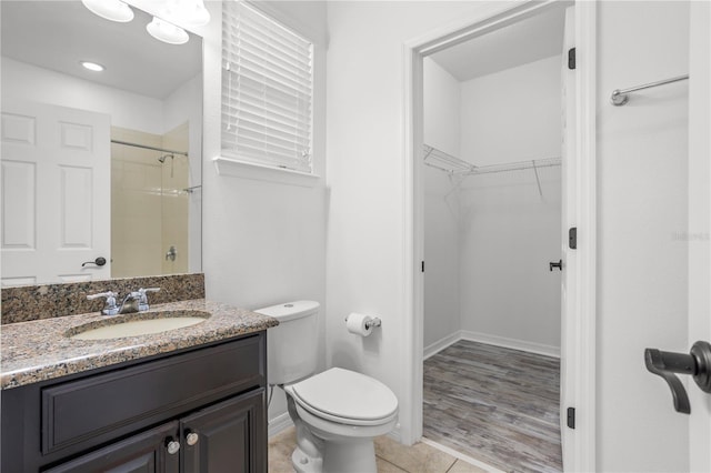 bathroom featuring tile patterned floors, toilet, a spacious closet, walk in shower, and vanity