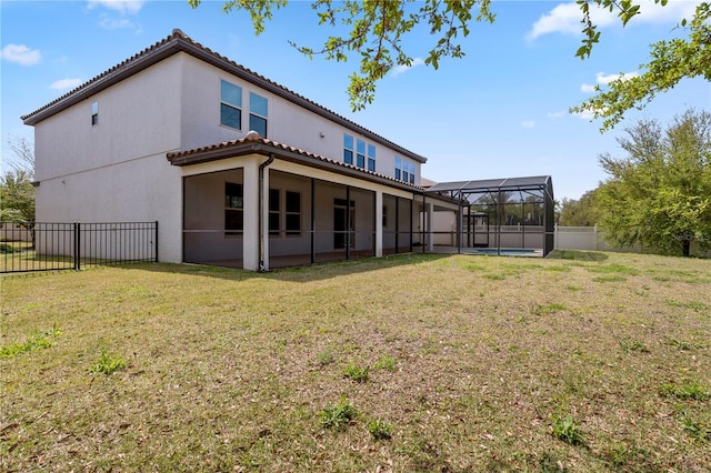 back of property featuring a tiled roof, stucco siding, glass enclosure, a yard, and a fenced backyard