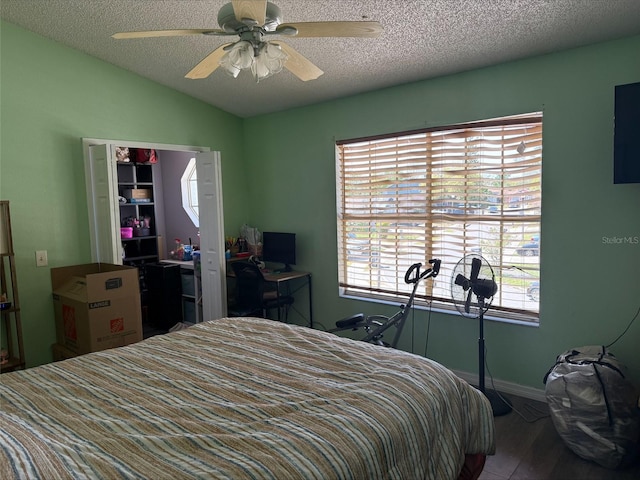 bedroom featuring a textured ceiling, wood finished floors, baseboards, ceiling fan, and vaulted ceiling