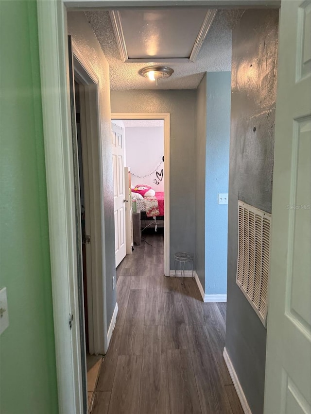 corridor featuring a textured ceiling, baseboards, and dark wood-style flooring