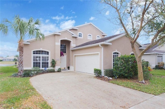 mediterranean / spanish-style home featuring stucco siding, driveway, a front yard, and an attached garage