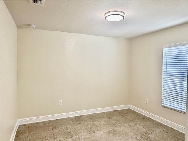 unfurnished room featuring visible vents, a textured ceiling, and baseboards