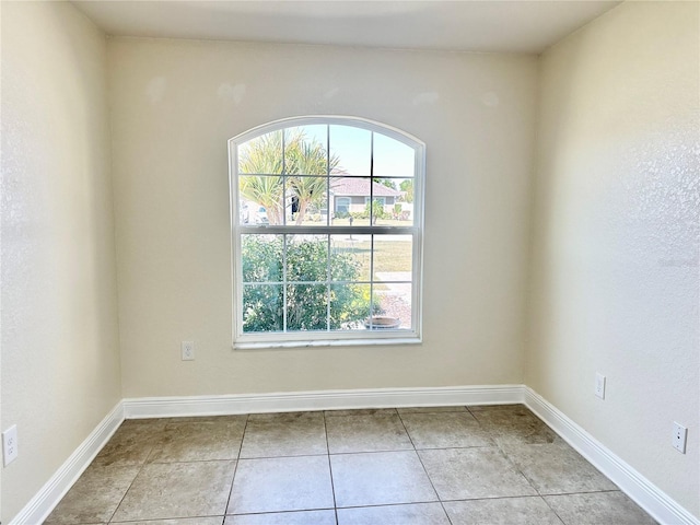 empty room with light tile patterned flooring and baseboards