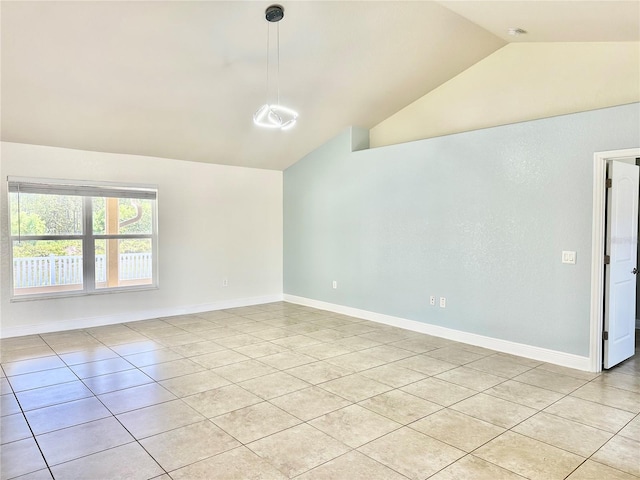 empty room with baseboards, lofted ceiling, and light tile patterned flooring