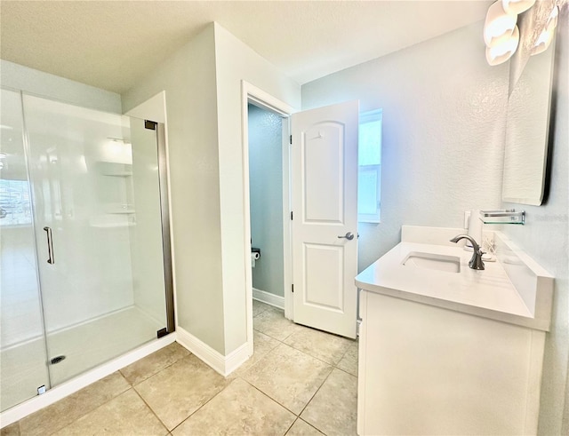 full bath featuring tile patterned floors, a stall shower, vanity, and baseboards