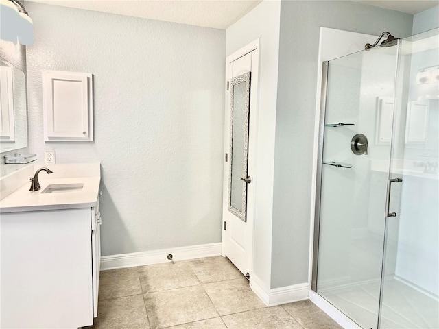 bathroom featuring tile patterned flooring, a stall shower, vanity, and baseboards