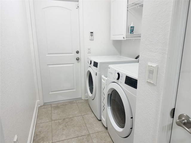 washroom featuring washer and dryer, light tile patterned flooring, and cabinet space