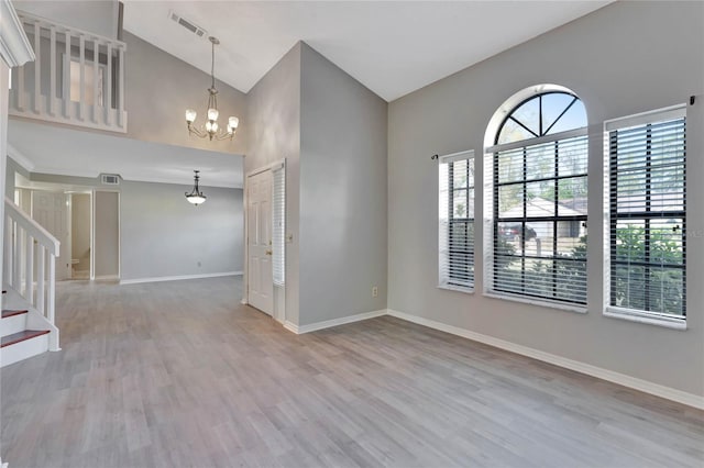 unfurnished room featuring high vaulted ceiling, wood finished floors, stairway, baseboards, and a chandelier