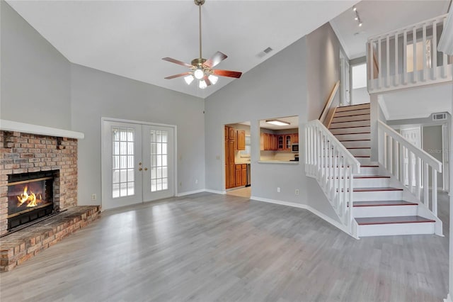 unfurnished living room with visible vents, ceiling fan, stairs, french doors, and light wood-type flooring