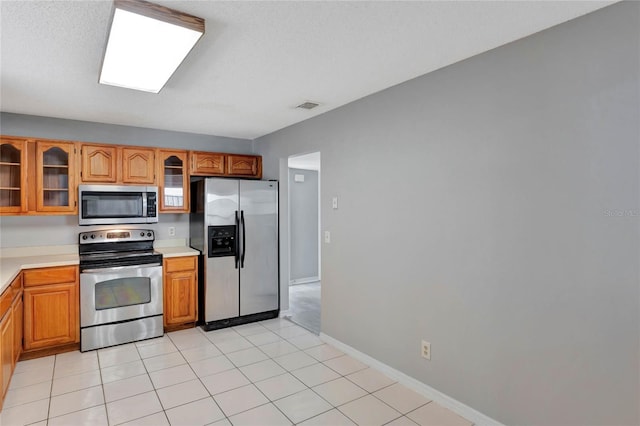 kitchen with light countertops, glass insert cabinets, visible vents, and stainless steel appliances