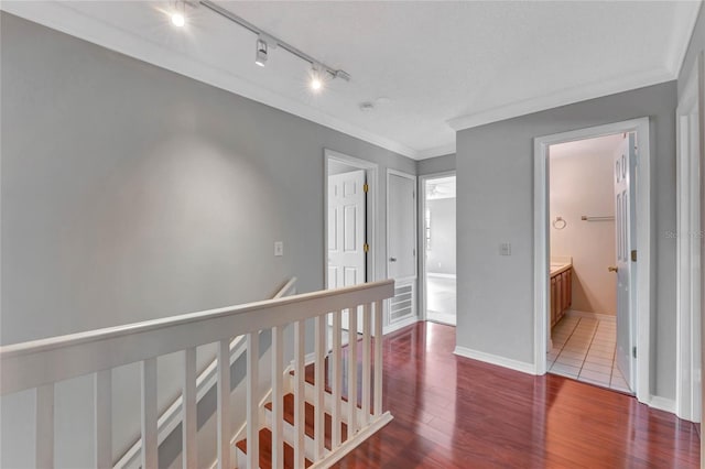 corridor with baseboards, an upstairs landing, wood finished floors, and crown molding