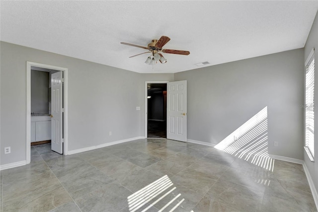 unfurnished bedroom featuring multiple windows, baseboards, visible vents, and a textured ceiling