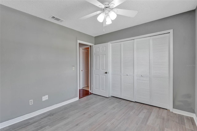 unfurnished bedroom featuring a textured ceiling, light wood-style floors, visible vents, and baseboards
