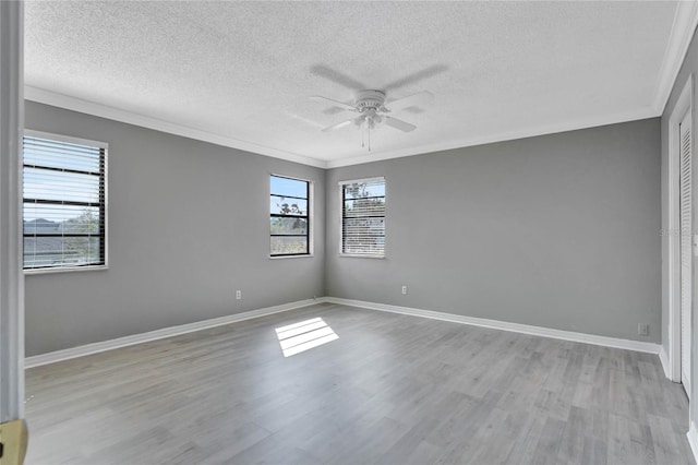 unfurnished room with crown molding, wood finished floors, a ceiling fan, and baseboards