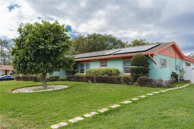 single story home featuring a front yard and roof mounted solar panels